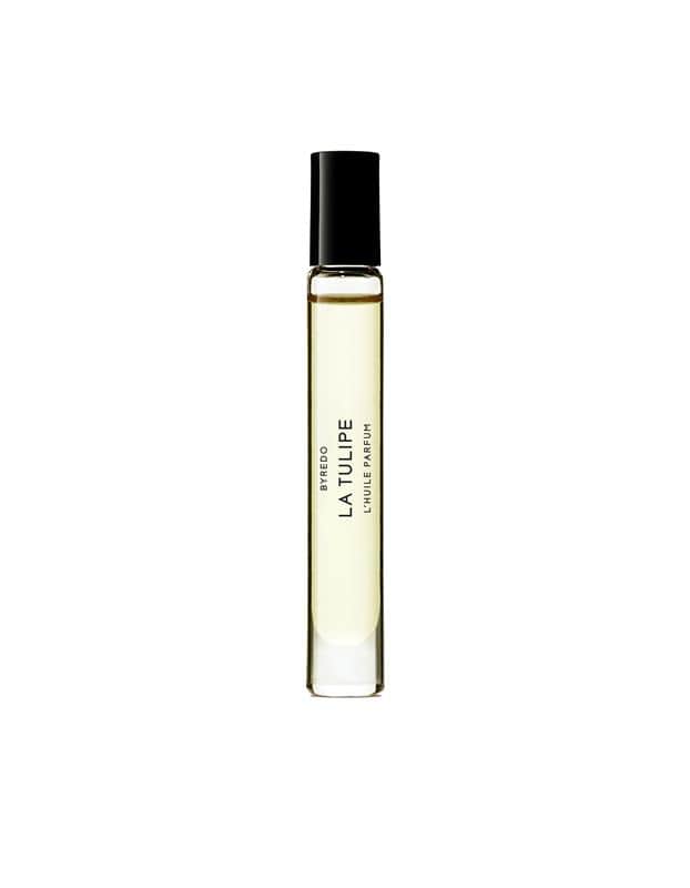 BYREDO La Tulipe Roll-on Perfumed Oil: A clear glass rollerball bottle with a black cap, filled with pale yellow perfumed oil and labeled "BYREDO LA TULIPE L'HUILE PARFUM