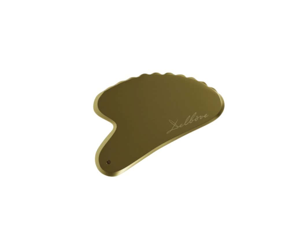 Gold-toned Gua Sha tool with scalloped edge for facial massage and skincare