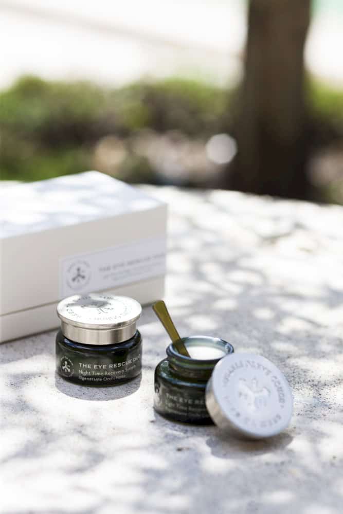 The Eye Rescue Duo night cream jars with a small spoon on a stone surface.