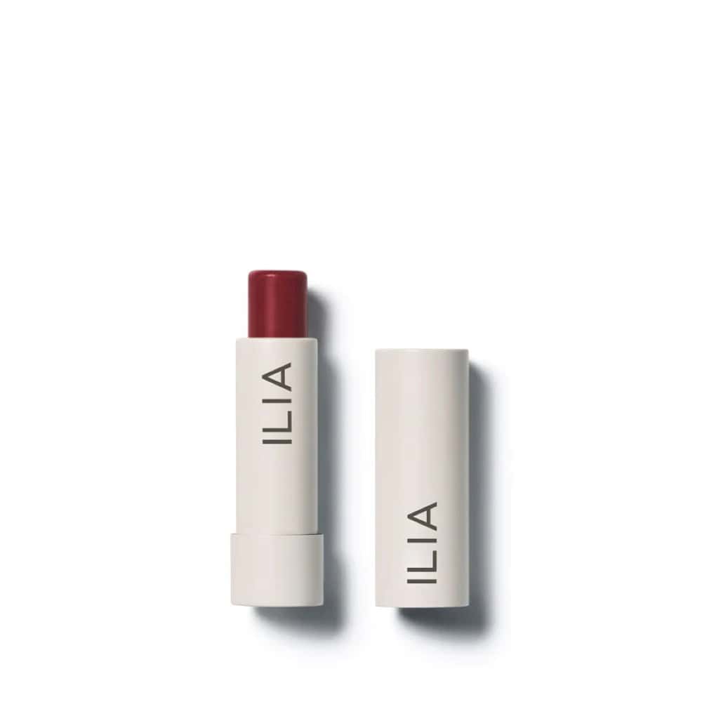 ILIA Balmy Tint Hydrating Lip Balm in a deep berry shade, with cap removed