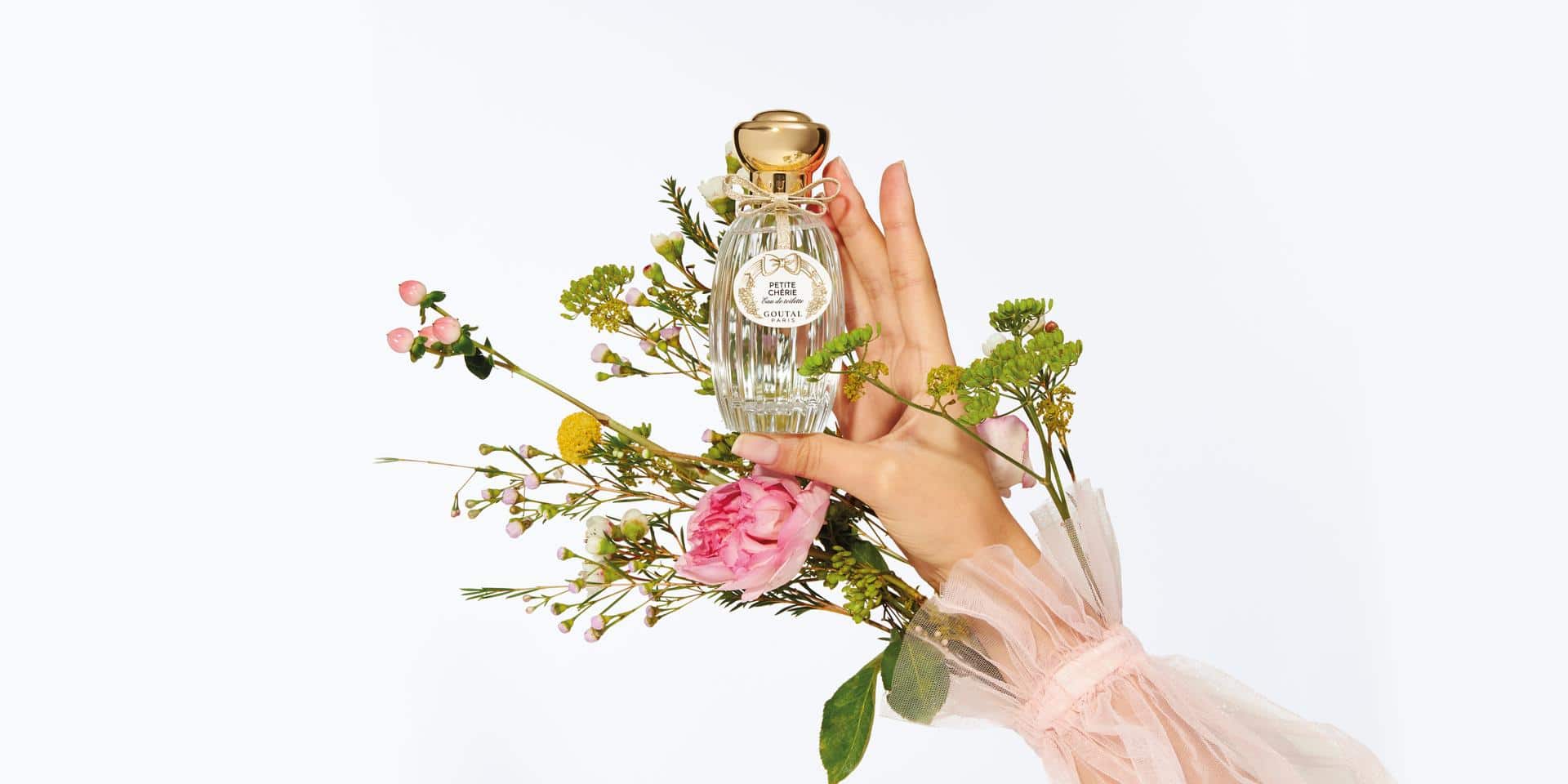 Woman's hand holding a crystal perfume bottle with flowers
