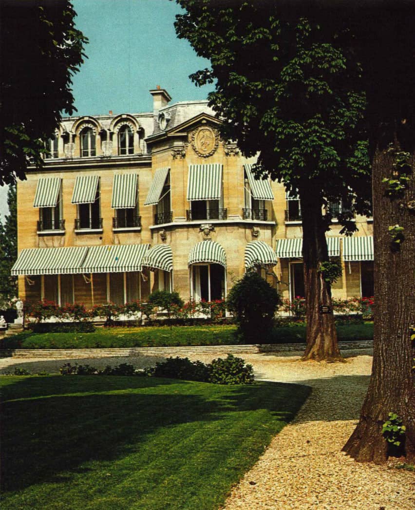 Elegant mansion with striped awnings and manicured gardens